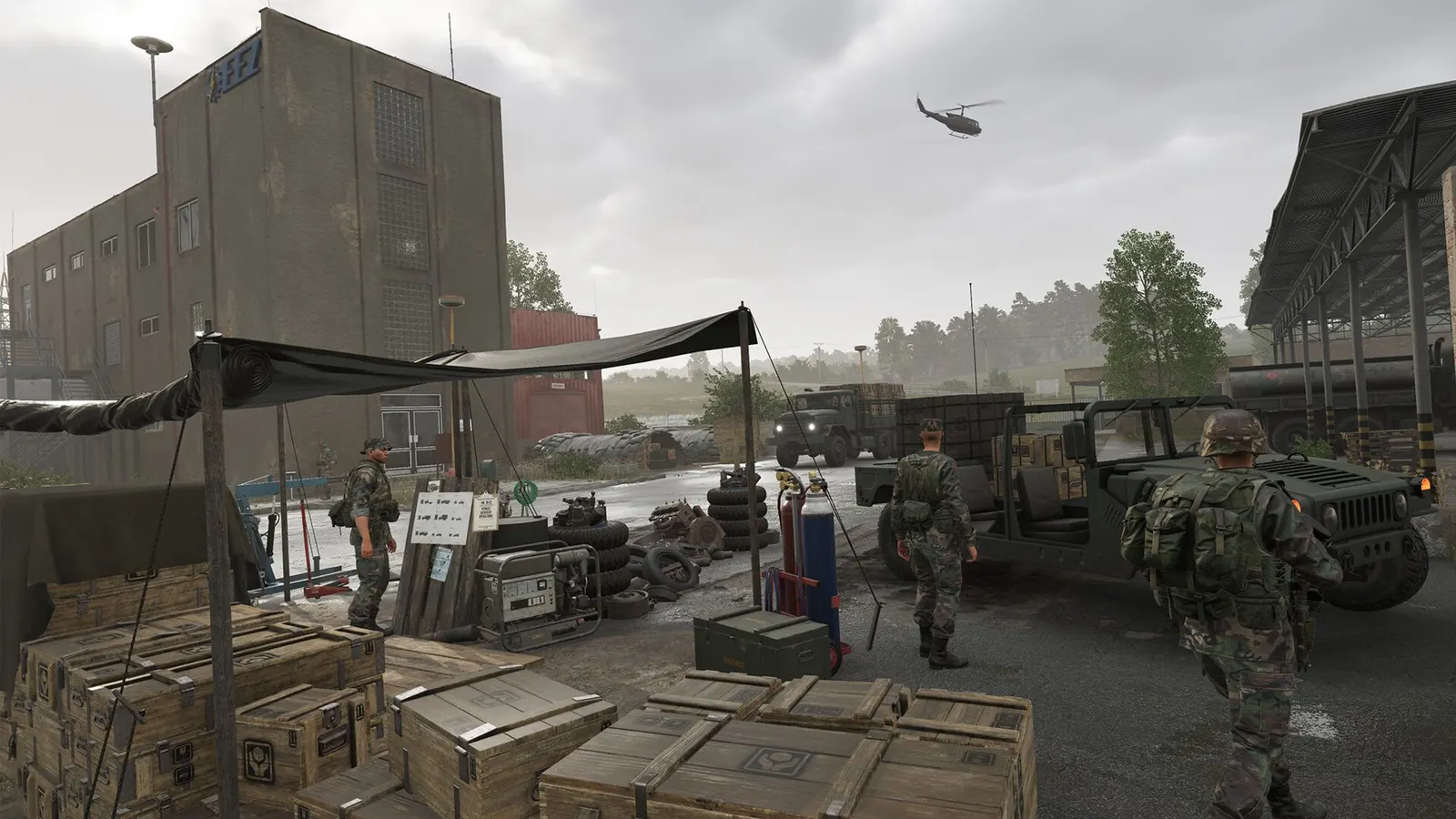 Soldaten in einer Basis mit Munitionskisten, einem Geländewagen und einem Lkw, im Hintergrund ein Hubschrauber